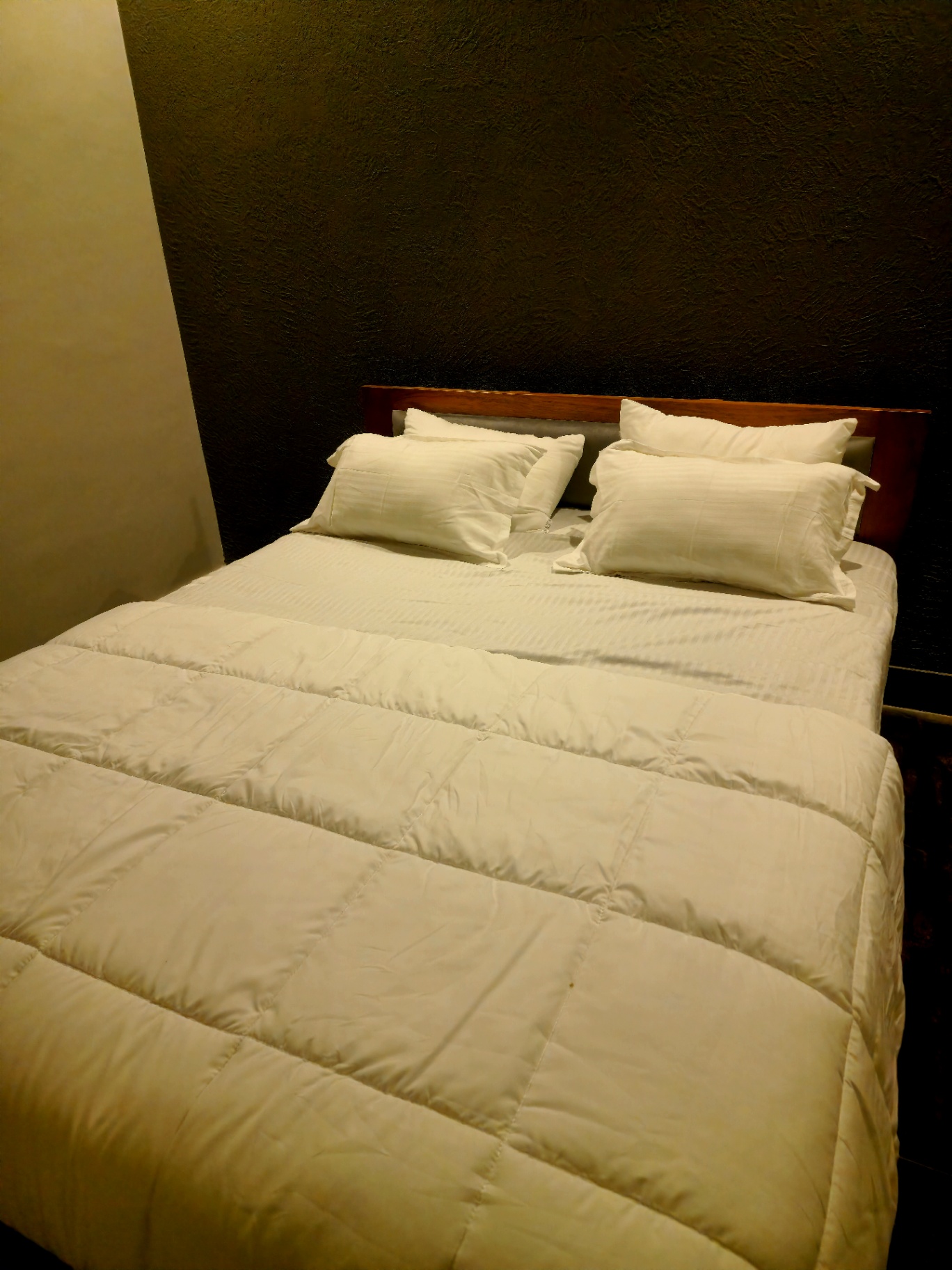 Boutique bedroom with premium linen and dark accent wall