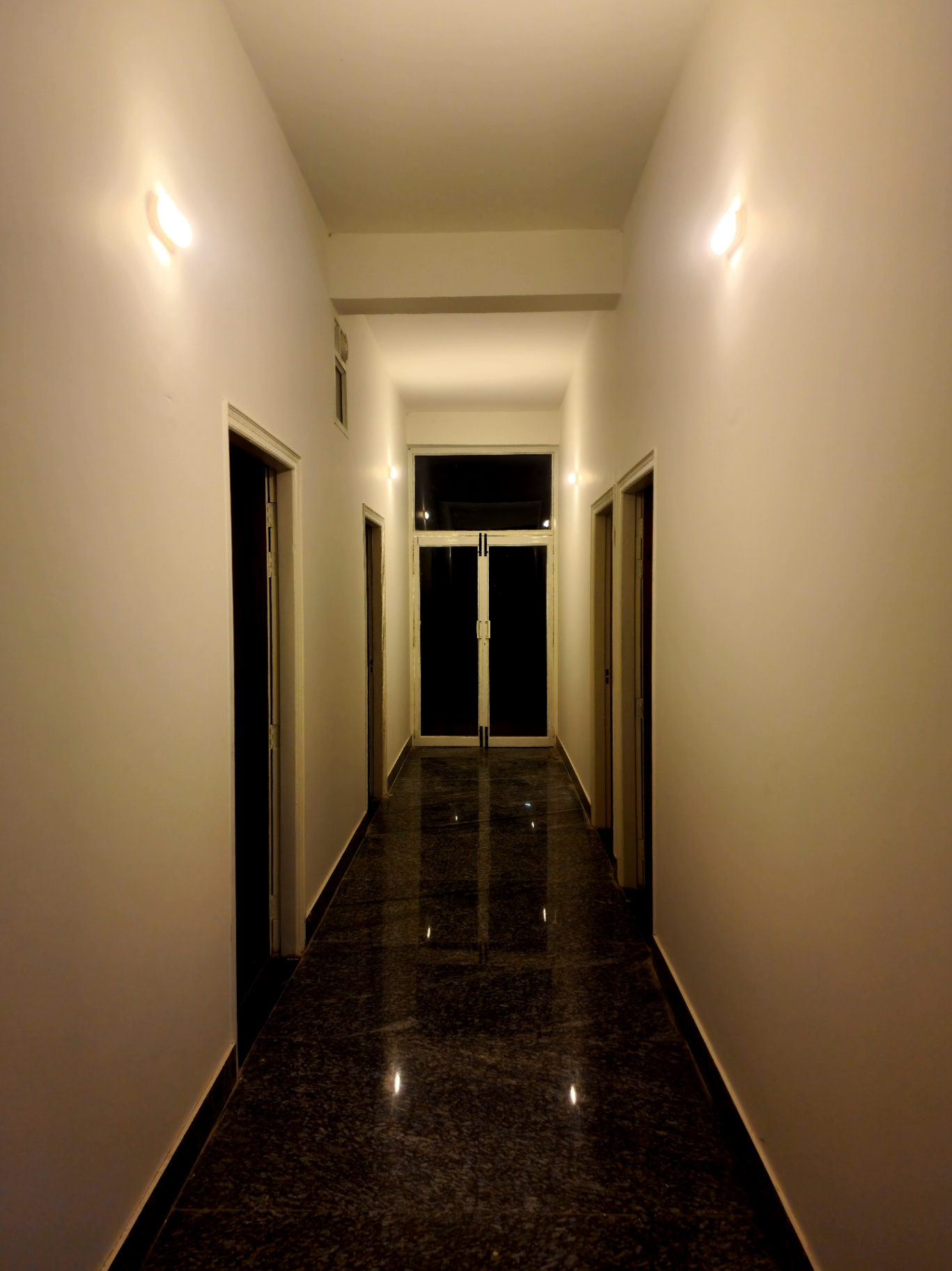 Bright, polished guest corridor with sconce lighting