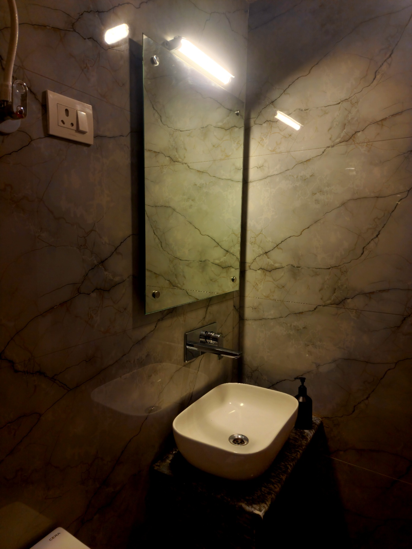 Designer vessel basin against marble walls